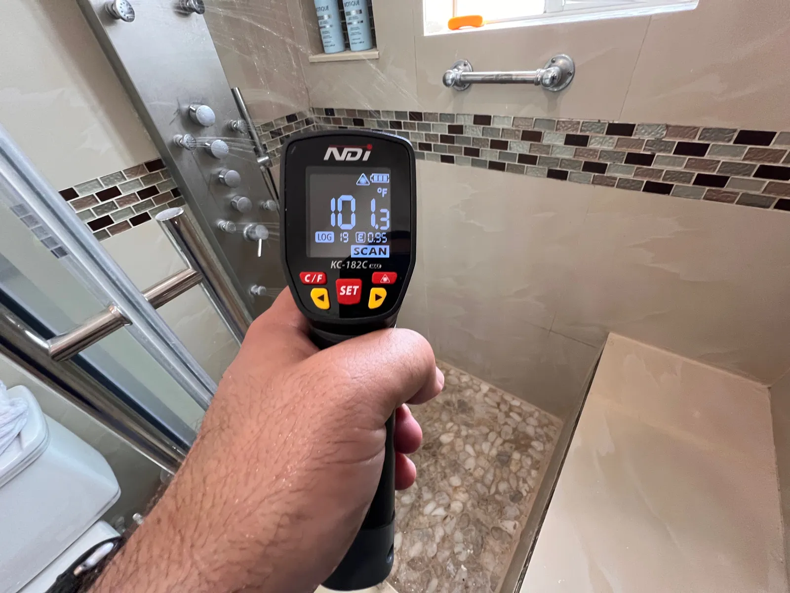 Infrared thermometer checking shower water temperature